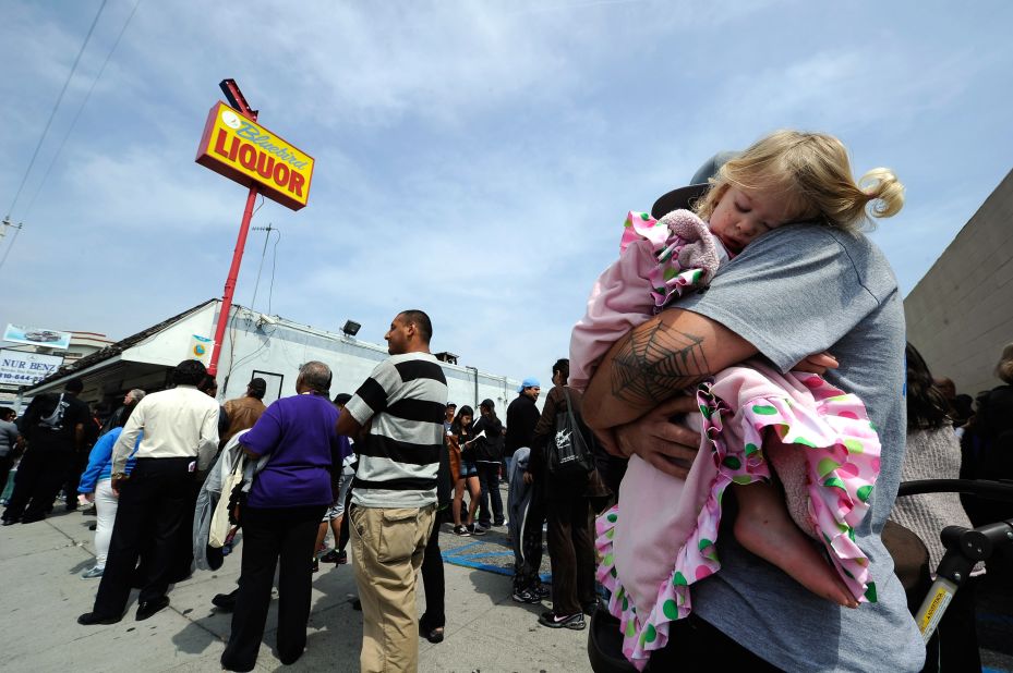 One year-old Karissa Sanchez sleeps on her father Chris' shoulder as they have been waiting over three hours to buy their Mega Millions lottery tickets at Bluebird liquor store.