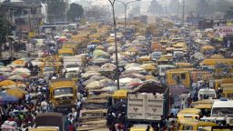 People walk struggling for space between buses and trucks at the popular Oshodi bus stop in Lagos.