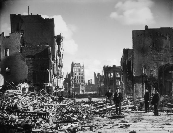 People stand in the rubble of collapsed buildings at the corner of Mason and Ellis streets on January 1, 1906, after the Great San Francisco Earthquake and fire.