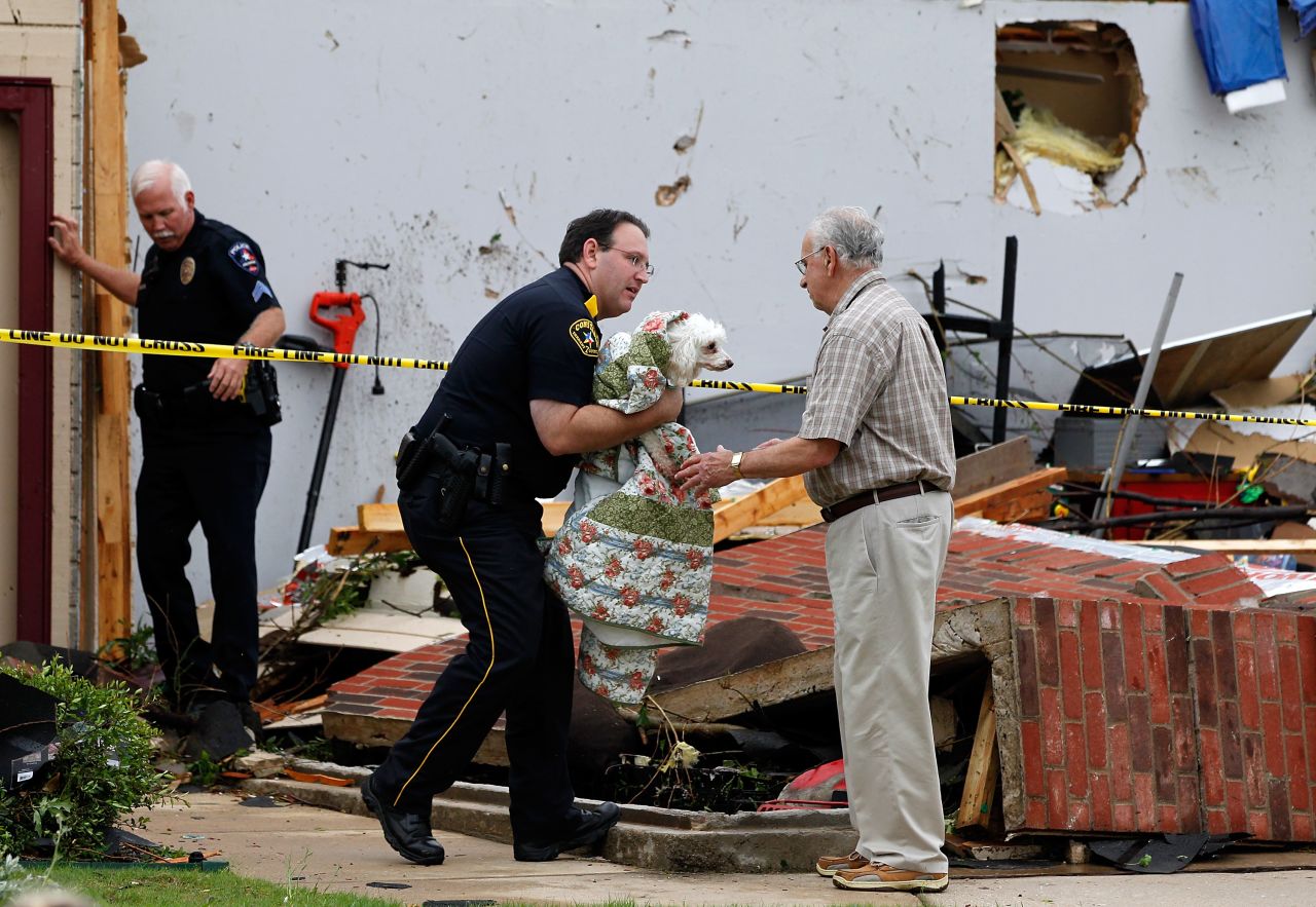 A police officer in Arlington returns a dog to David Lowe after it was rescued from the rubble of his daughter's home.