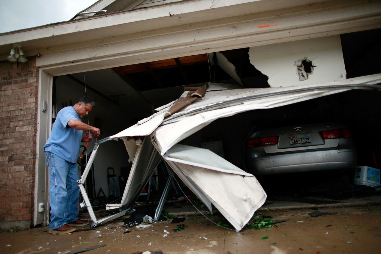 A man in Arlington works to clean up his garage after it was damaged by a tornado.