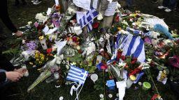 Greek flags along with flowers, candles and hand written messages lay on April 5, 2012 at the foot of a cypress tree where a retired pharmacist, had shot himself at Athens central Syntagma square. The 77-year-old, killed himself yesterday morning in the busiest public square of the Greek capital, opposite to the Greek Parliament, which for two years has been the main rallying point for demonstrations against government austerity measures. Greek newspapers on Thursday printed excerpts from a note, allegedly found in the pensioner's pocket, in which he accused the government of leaving him in penury and compared the administration to the regime imposed by Greece's Nazi German occupiers in 1941. AFP PHOTO / LOUISA GOULIAMAKI (Photo credit should read LOUISA GOULIAMAKI/AFP/Getty Images)