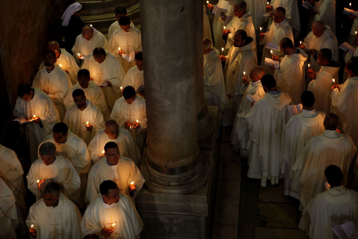 Roman Catholic clergymen hold candles as they circle the Stone of Anointing during the Holy Thursday Mass at the Church of the Holy Sepulchre in Jerusalem's Old City.