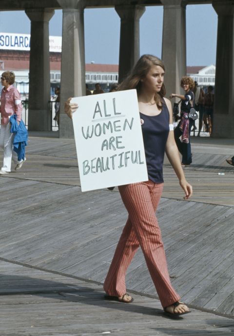 <strong>All women are beautiful: A protest against the Miss America Pageant at Atlantic City, New Jersey, September 6,1969:</strong> A woman walks past with a sign reading 'All women are beautiful'.