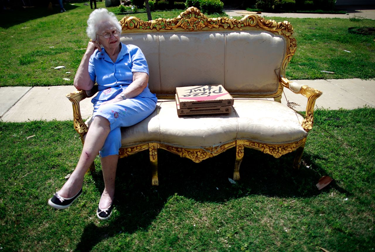 Nelda Vines sits in a chair in the front lawn of a home while waiting for several family members who were visiting a tornado-ravaged neighborhood.