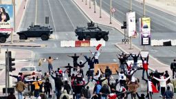 Anti-government protestors open their arms in front of military vehicles near Pearl Square in Manama, Bahrain, on March 16, 2011.