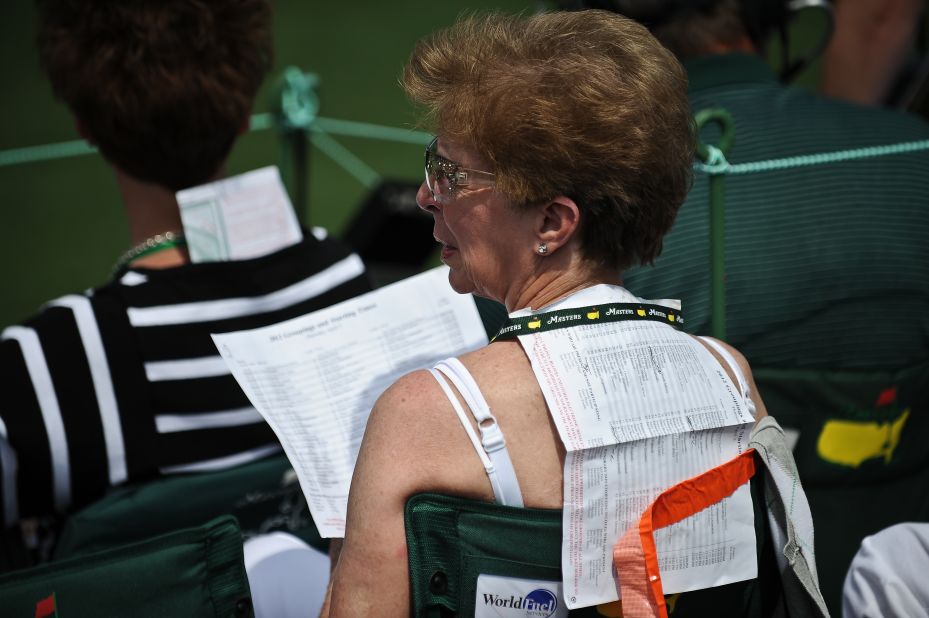 A woman uses a start list to protect herself from the sun during Thursday's opening round.