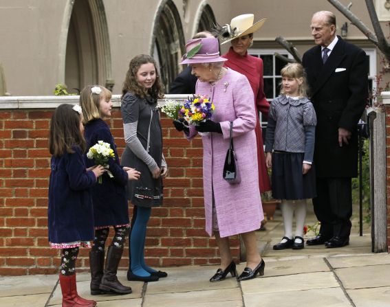 Queen Elizabeth II receives flowers from young people while her husband, Prince Philip, Duke of Edinburgh, daughter-in-law, Sophie, Countess of Wessex, and granddaughter Lady Louise Windsor look on as they leave Saint George's Chapel in Windsor Castle after attending the Easter service. 