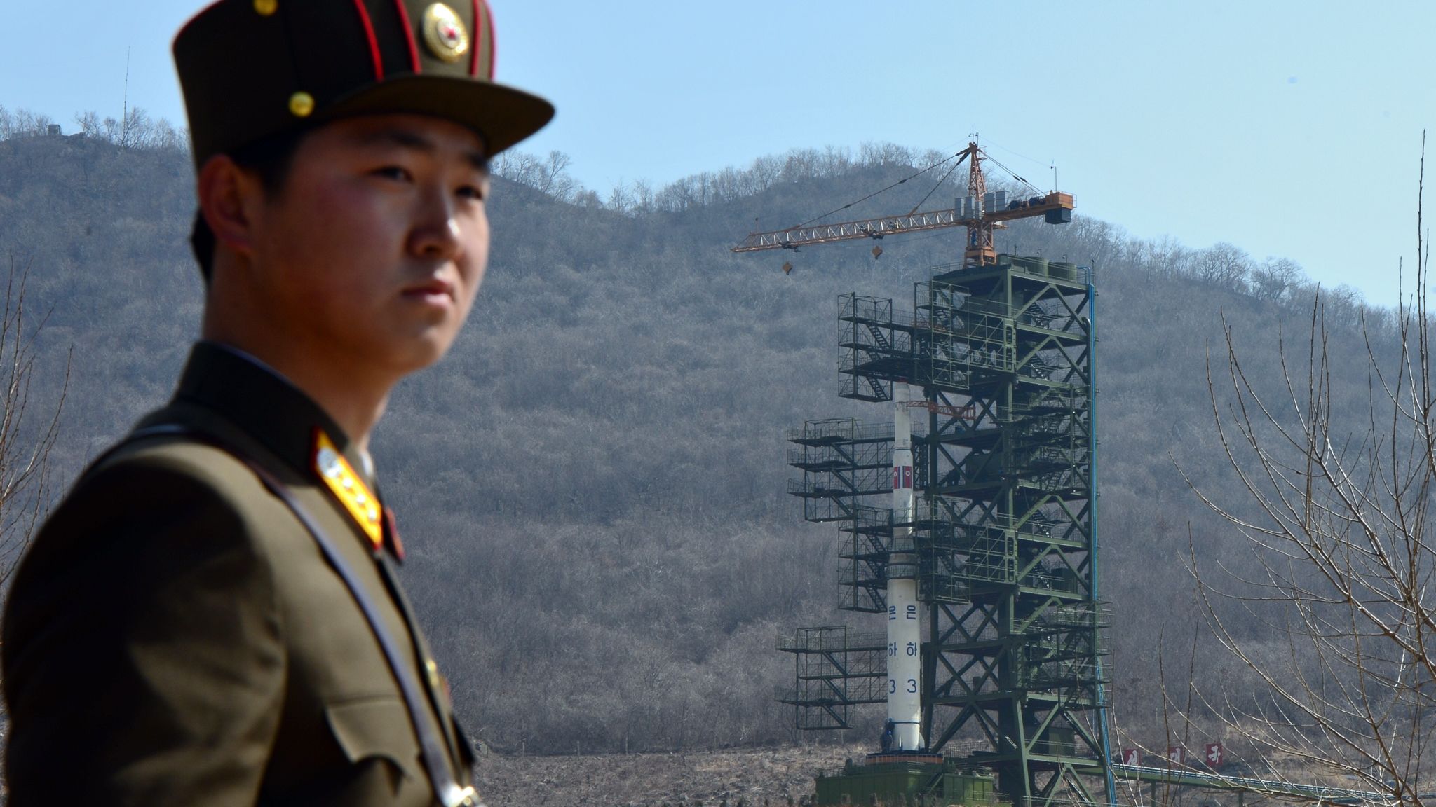 A North Korean soldier stands guard Sunday in front of the Unha-3 rocket in Tongchang-ri.