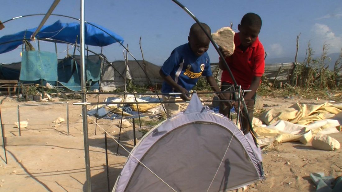 Two boys at the tent city orphanage work to fix their tent blown away by strong winds. 