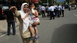An Acehnese woman with a child tries to stop a car to go to higher ground shortly after an earthquake hit the western coast of Sumatra in Banda Aceh on April 11, 2012.