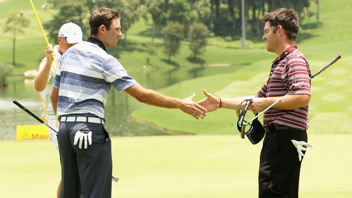 Louis Oosthuizen and Charl Scwartzel (left) shake hands at the end of the first round of the Malaysian Open.