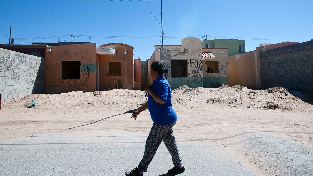 A woman walks past grafitti-covered houses in an abandoned neighborhood in Ciudad Juarez.