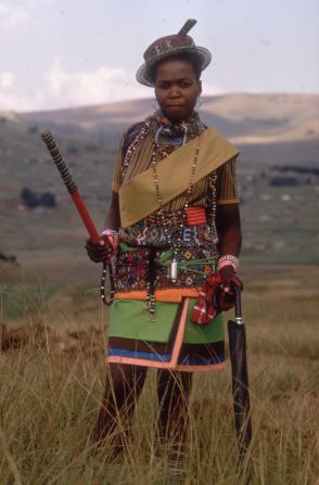 A young Zulu woman, wearing samples of her colorful beadwork, poses en route to a traditional wedding. 