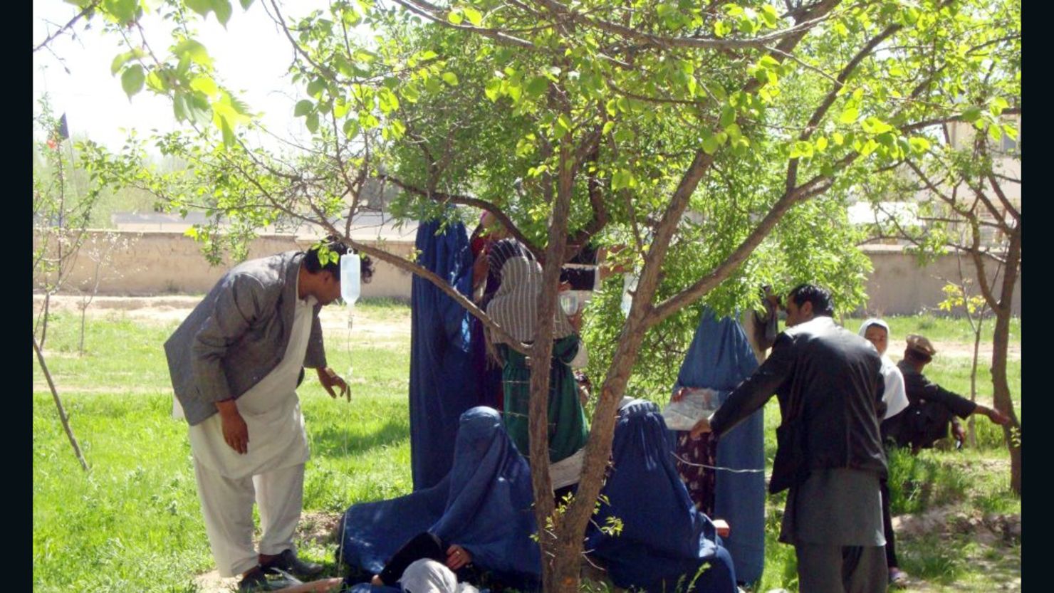 Sickened women receive treatment Tuesday in a courtyard in northeast Afghanistan; IV bags are hung from tree branches.