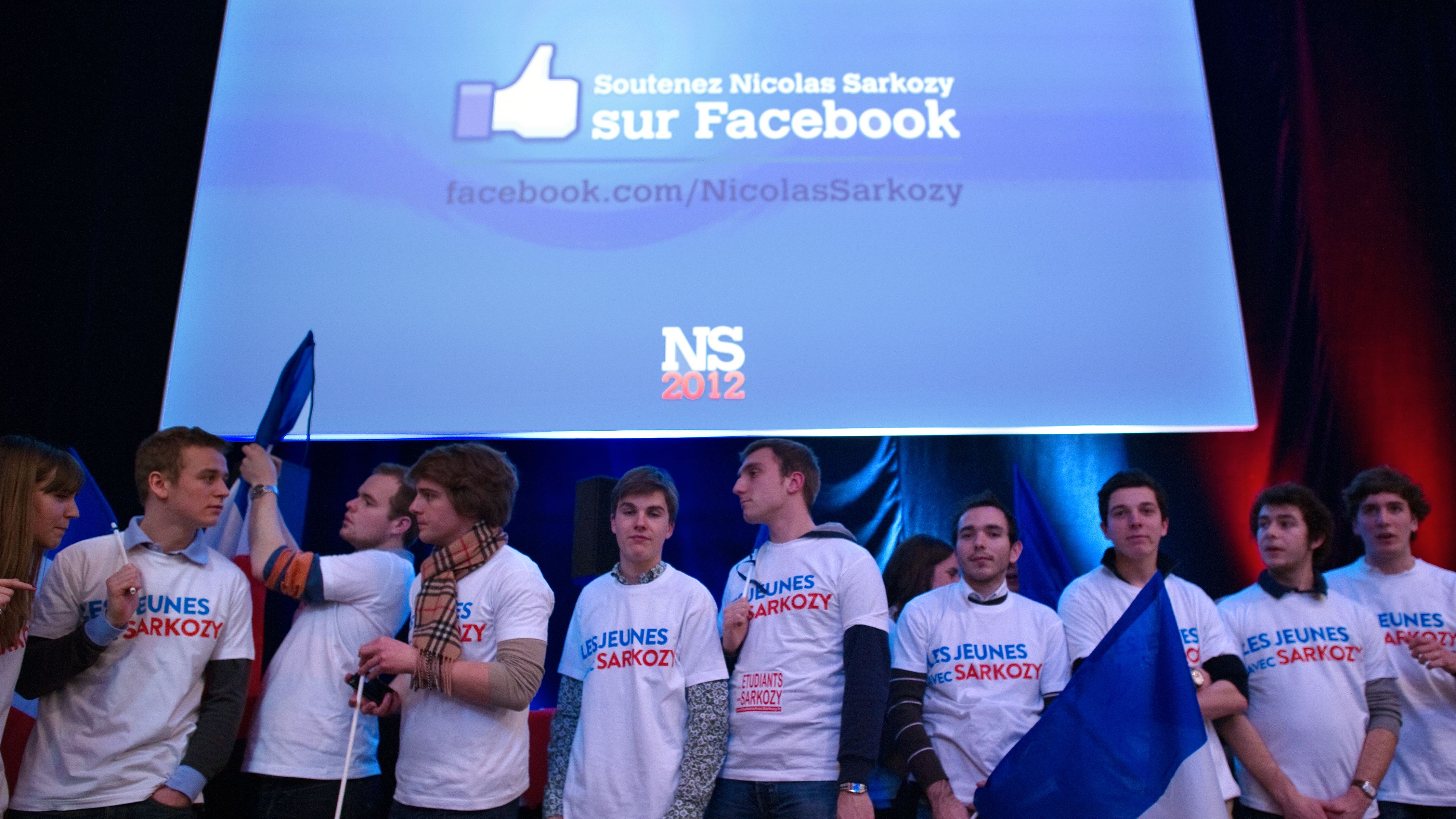 Young supporters wait for Nicolas Sarkozy, as a giant screen provides his Facebook adress during a campaign meeting in Lille.