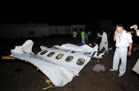 A Pakistani airline official, right, stands next to the wreckage of the Bhoja Air Boeing 737 plane. Debris and body parts were scattered across the crash site as workers sifted through the wreckage in the heavily populated residential area.