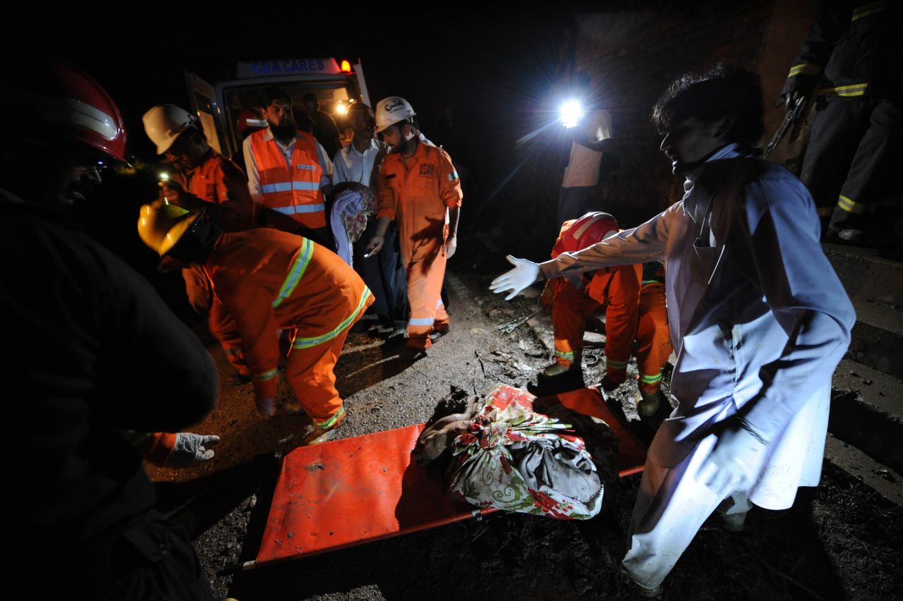 Pakistani rescue workers remove the covered remains of crash victims.
