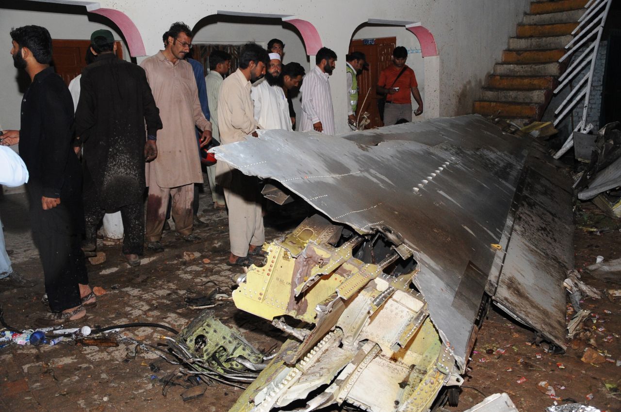 Pakistani villagers survey debris from the crash.