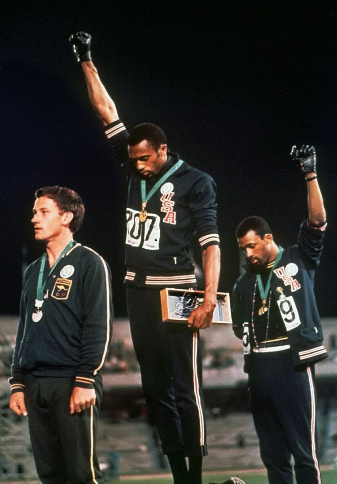 Tommie Smith, center, and John Carlos, right, raise their fists while standing on the podium at the 1968 Mexico Olympics.