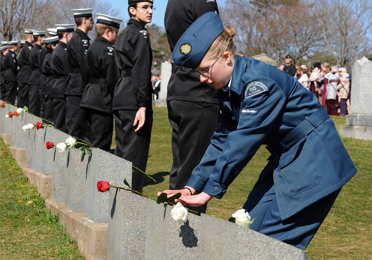 A young cadet places a rose on the headstone of one of the Titanic gravesites during a Titanic Spiritual Ceremony at the Fairview Lawn Cemetery in Halifax.