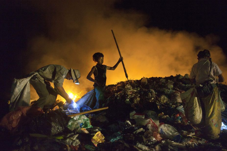 Cambodians work late into the night recycling garbage as fires burn at the local garbage dump. Many children work part time in the dump to help support their families while attending school during the day.