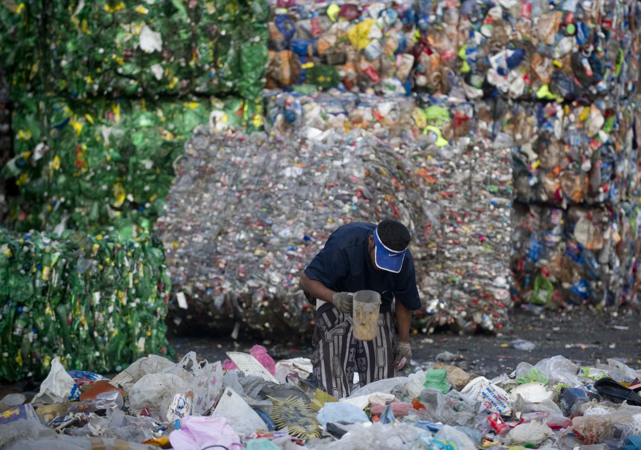 A scavenger classifies refuse in front of a pile of compacted bales of plastic bottles at the Bordo Poniente garbage dump in Mexico City. Some 6,000 tons of garbage from the second world's most populated city was deposited here daily for about 25 years until it was closed by the government in December 2011. The dump was considered one of the main sources of greenhouse gases in Mexico.