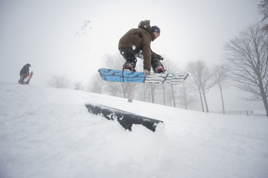 An employee of the Seven Springs Golf Resort snowboards off the seventh green in Somerset on Monday. 