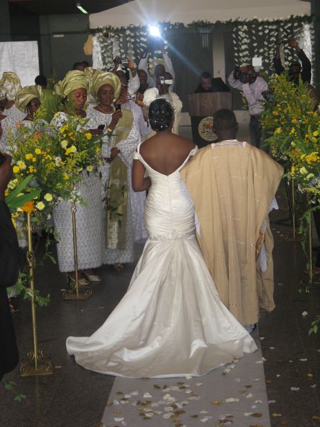 A Nigerian couple make their way up the aisle, with the bride wearing a white gown and the groom in traditional attire.