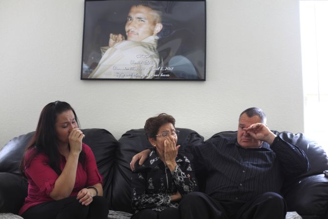 A picture of Daniel Adkins Jr. hangs above the wall in his family home. His sister, Marina Reyes; mother, Antonia Adkins; and father, Daniel Adkins Sr., want the man who shot their son to face charges. 