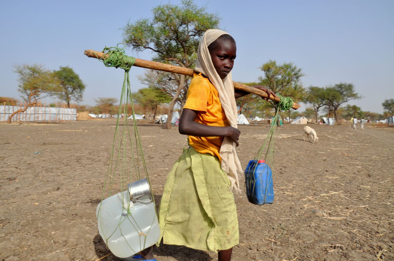 Women and girls wait in the hot sun for up to four hours, twice a day, to collect their families' water rations.