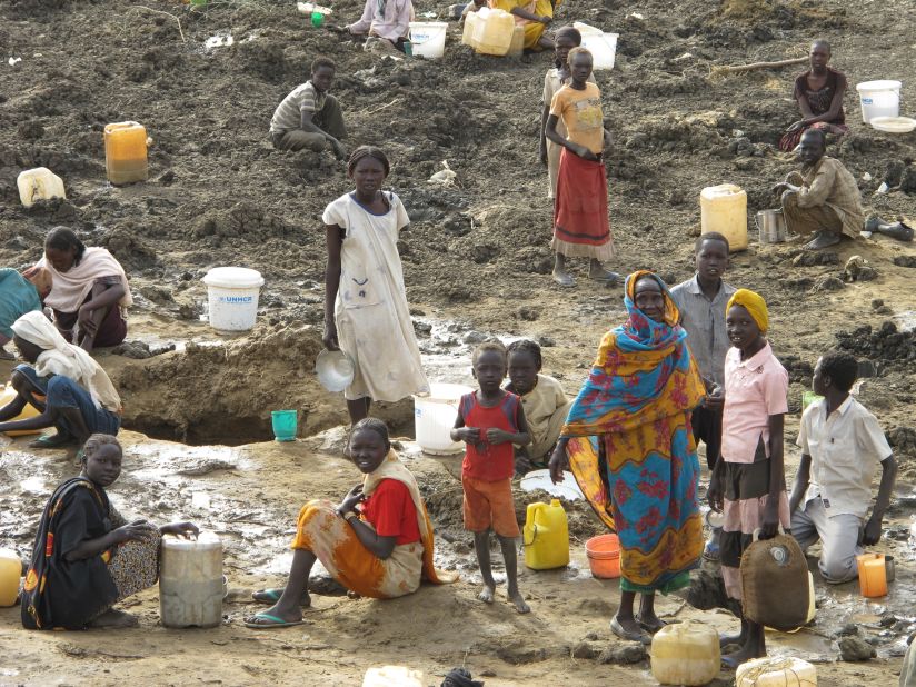 Refugees are left digging around the bottom of a dried-up cattle pond to try and supplement their meager water supplies.