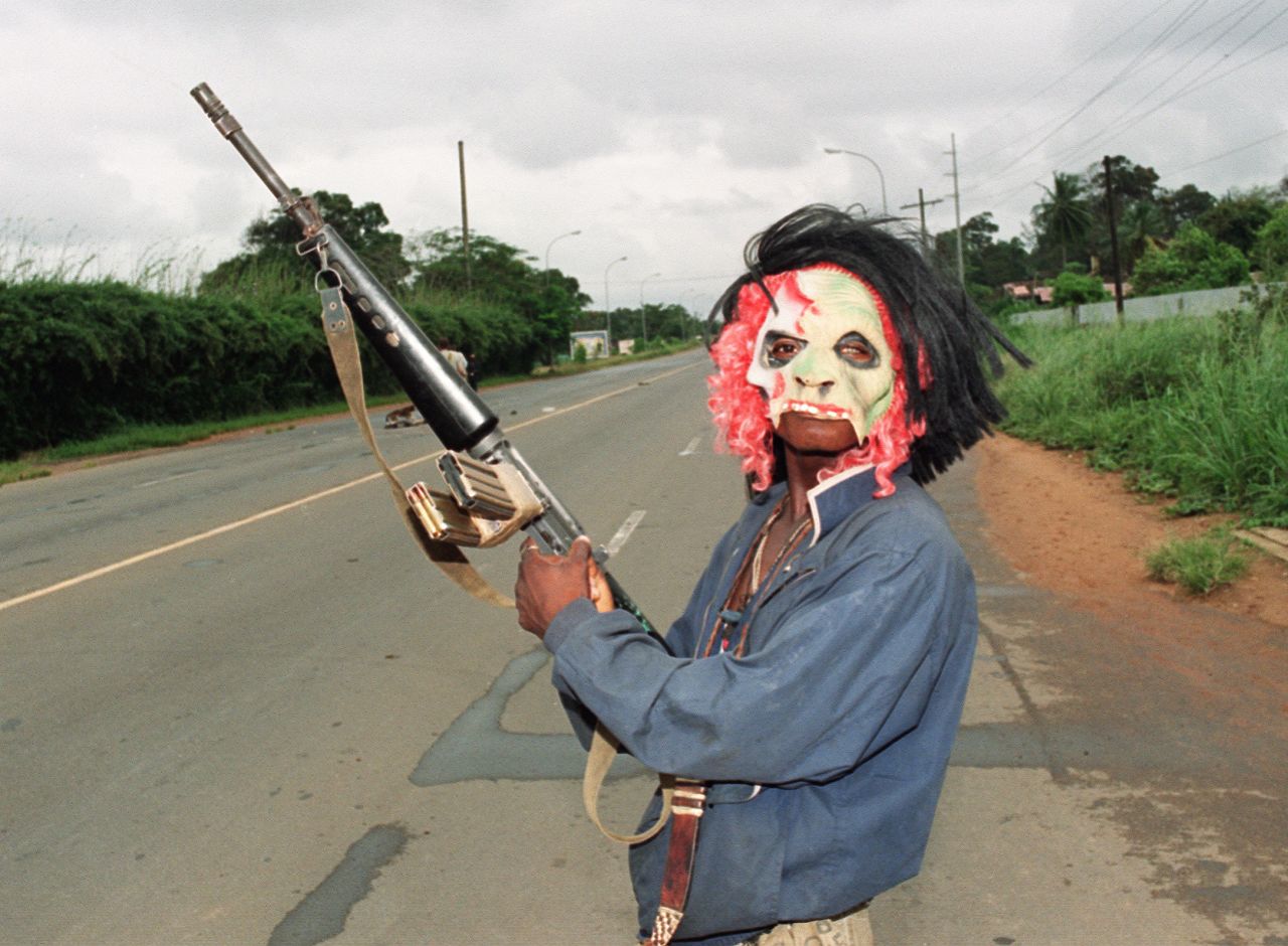 A masked rebel loyal to warlord Charles Taylor patrols in the streets of Monrovia in August 1990.