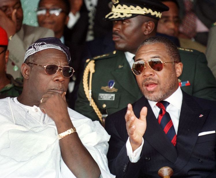 Liberian President Charles Taylor, right, chats to Nigerian counterpart Olusegun Obasanjo during a symbolic bonfire to destroy weapons in Monrovia in July 1999.