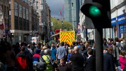 Members of the public gather on Tottenham Court Road in central London on April 27, 2012, as police seal off the street amid reports of an armed man causing a disturbance. 