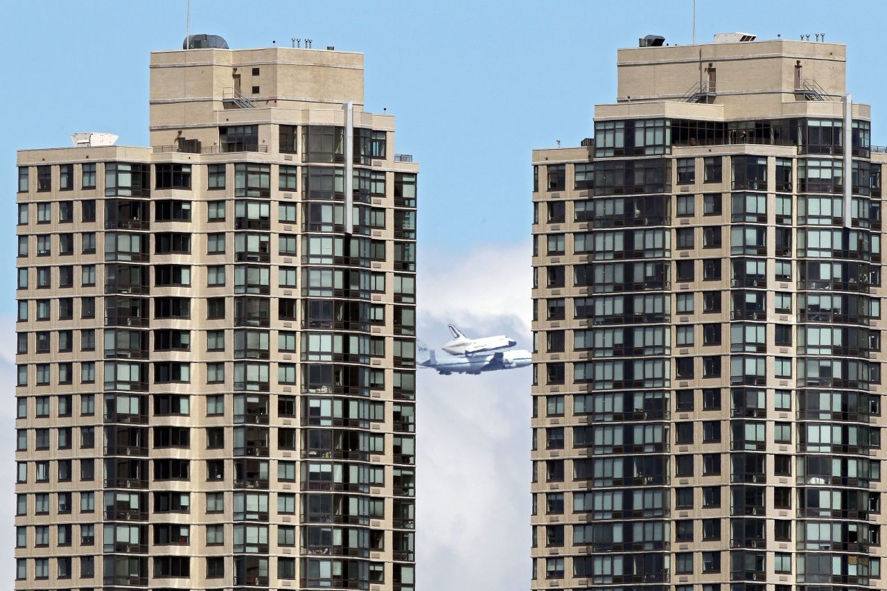 The space shuttle flies past the Jersey City skyline on the last leg of its final flight Friday.