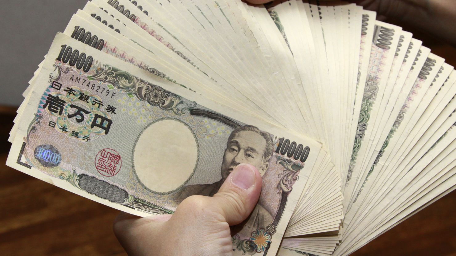 A bank teller counts 10,000 yen (118 USD) bank notes in Tokyo on September 22, 2010. 