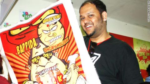 Abhijeet Kini, a comic book illustrator, poses with a poster of some of his original work like "Angry Maushi" and "Bappida."