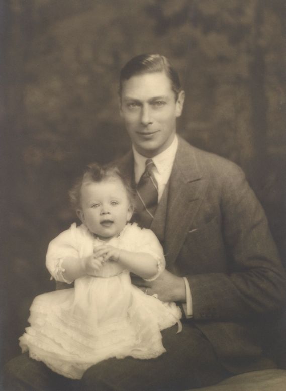 Prince Albert, later King George VI, proudly sits for a photograph with his young daughter and future monarch, Elizabeth.