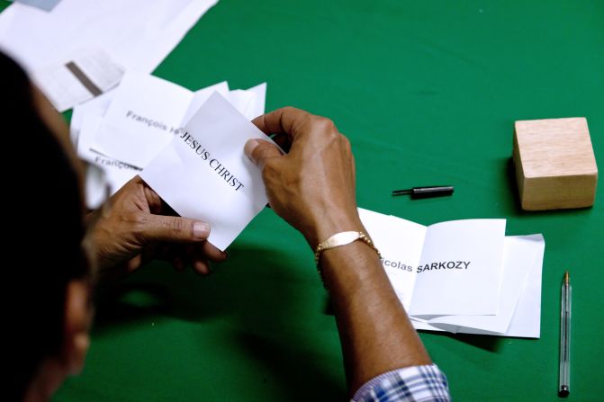 In South America, a scrutineer unfolds a ballot for "Jesus Christ" as he counts votes in French Guiana's Remire-Montjoly.