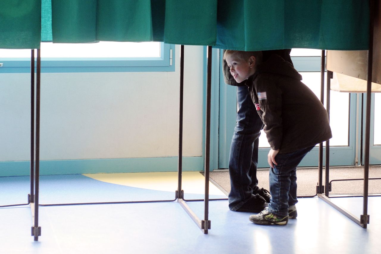A child looks under the curtain of a voting booth in Henin-Beaumont, France, near the border with Belgium.