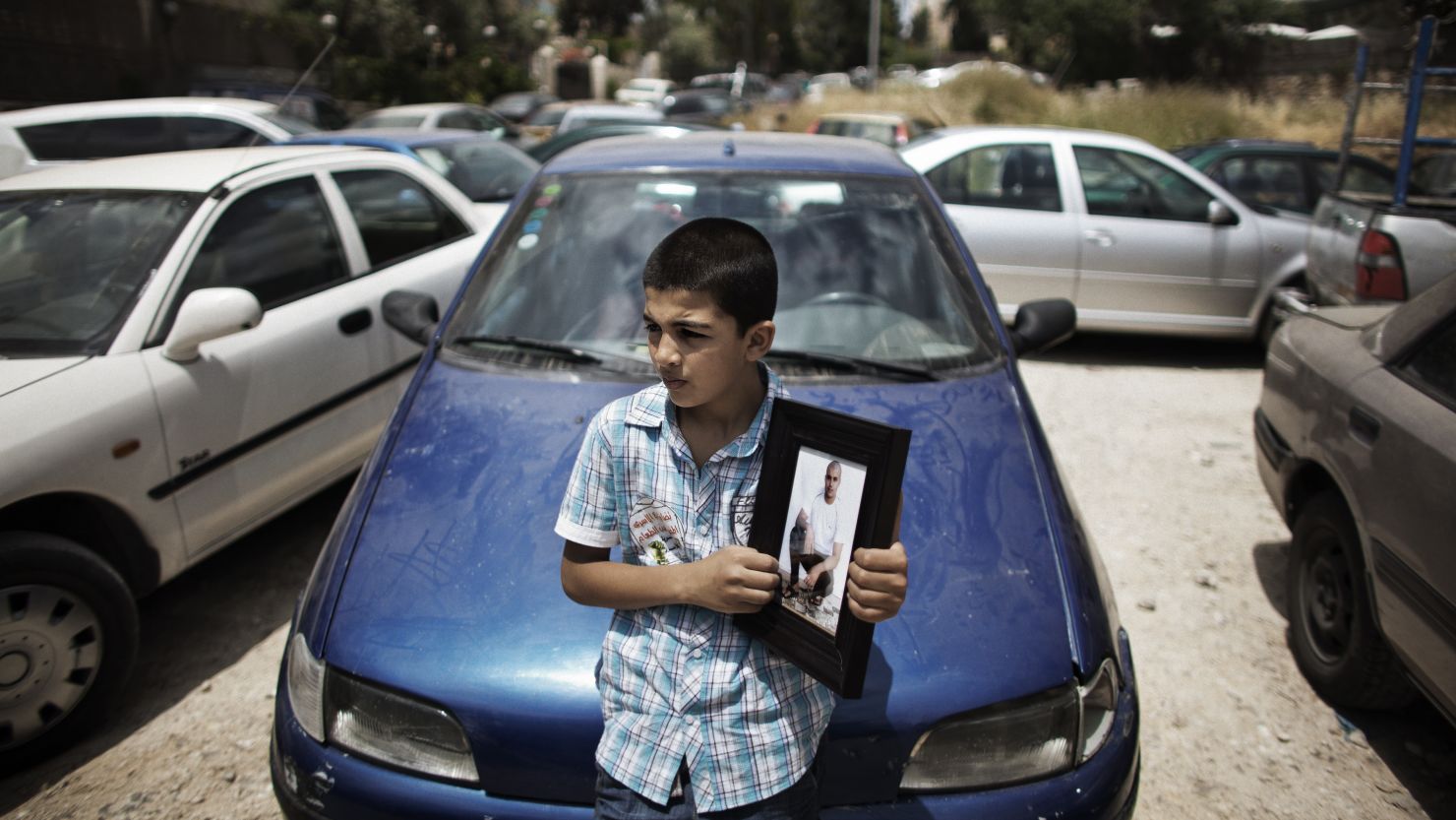 A Palestinian boy in Jerusalem holds a portrait Friday of a relative who's being held in an Israeli jail.