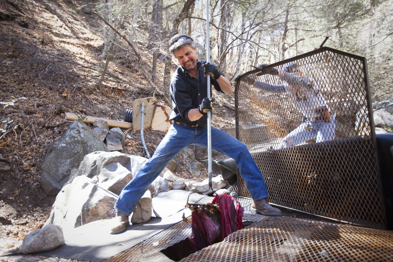 Rudd pulls a discarded jacket from one of Tombstone's springs in Carr Canyon near Sierra Vista. Tombstone city employees frequently have to drive into the mountains to check the springs for leaks, debris and vandalism.