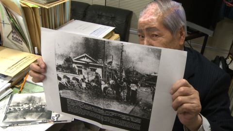Sunao Tsuboi, who suffered horrific burns in Hiroshima, holds a photo of himself and friends taken hours after the explosion.