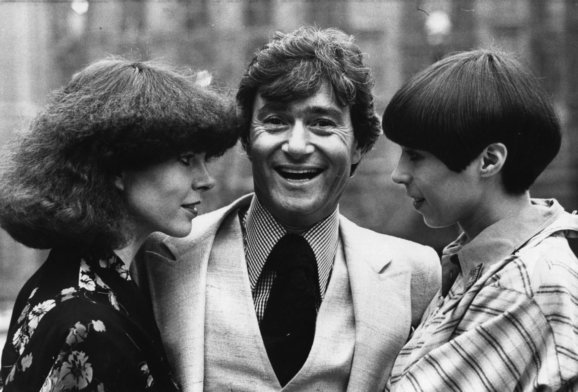 Vidal Sassoon stands between two contrasting examples of his hairdressing at a teach-in at the Albert Hall, where he returned to hairdressing after a five-year break in 1975. 