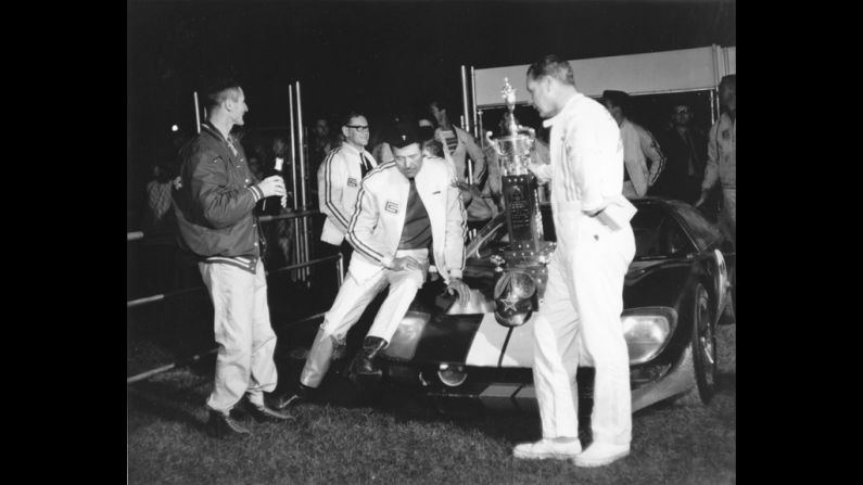 Shelby sits on the front of his Ford GT-40 after drivers Ken Miles, left, and Lloyd Ruby drove it to victory in the Daytona Continental in 1965.