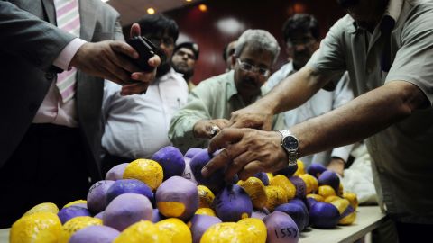 Pakistan customs officials display seized heroin concealed inside tape and balloons in Karachi.