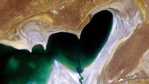 A satellite image features the heart-shaped northern tip of the western half of the Large Aral Sea (or South Aral Sea) in Central Asia. Once the world's fourth-largest inland body of water, the Aral Sea has been steadily shrinking over the past 50 years since the rivers that fed it were diverted for irrigation. In 2005, a dam was built between the sea's northern and southern sections to help improve water resource management and reverse the man-made environmental disaster. The dam allowed the river to feed the northern Aral, which has begun to recover. It hasn't solved the entire problem though, as the southern section is expected to dry out completely by 2020. The whitish area surrounding the lakebed is a vast salt plain, now called the Aralkum Desert, left behind by the evaporating sea. It comprises some 40 000 sq km zone of dry, white salt and mineral terrain. Each year violent sandstorms pick up at least 150 000 tonnes of salt and sand from Aralkum and transport them across hundreds of kilometres, causing severe health problems for the local population and making regional winters colder and summers hotter.
