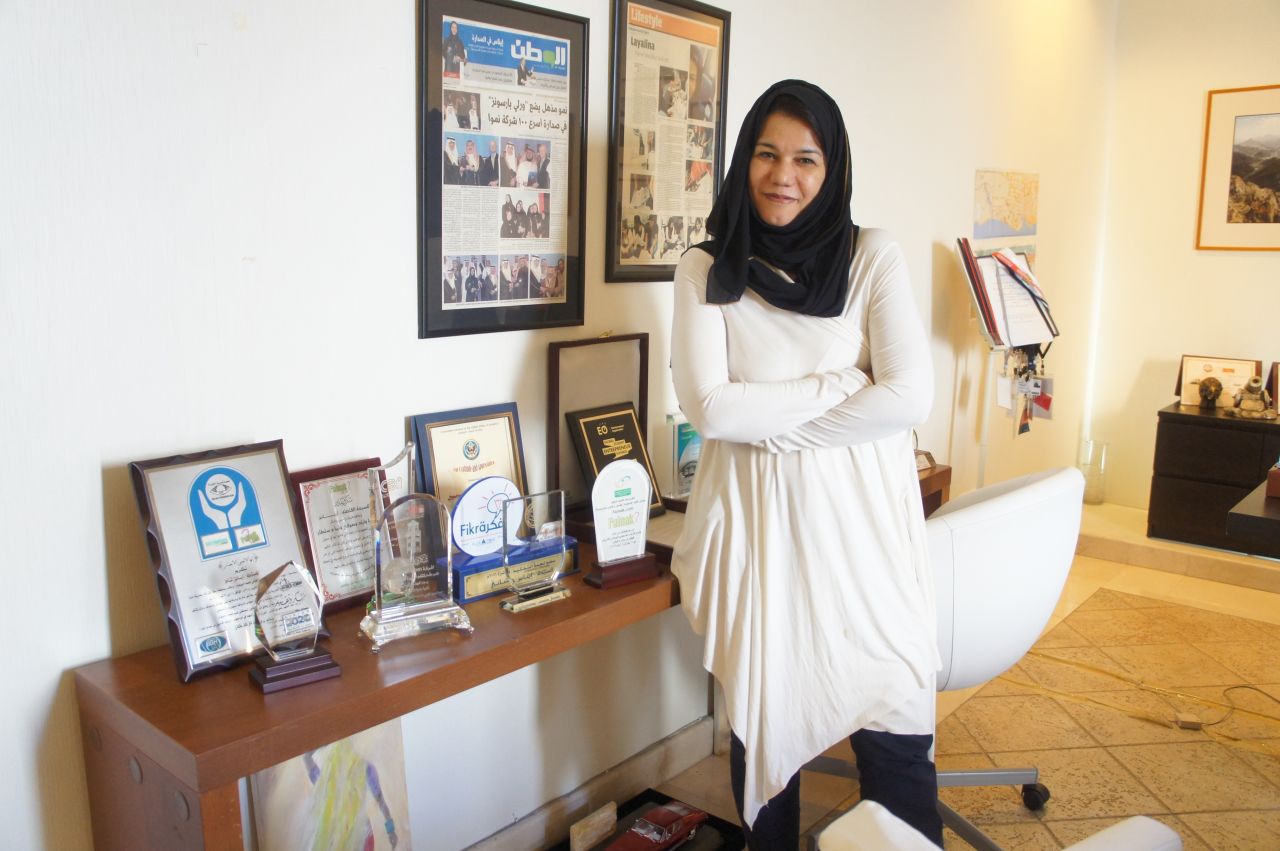 Rumman CEO Enas Hashani stands beside some of the company's awards.