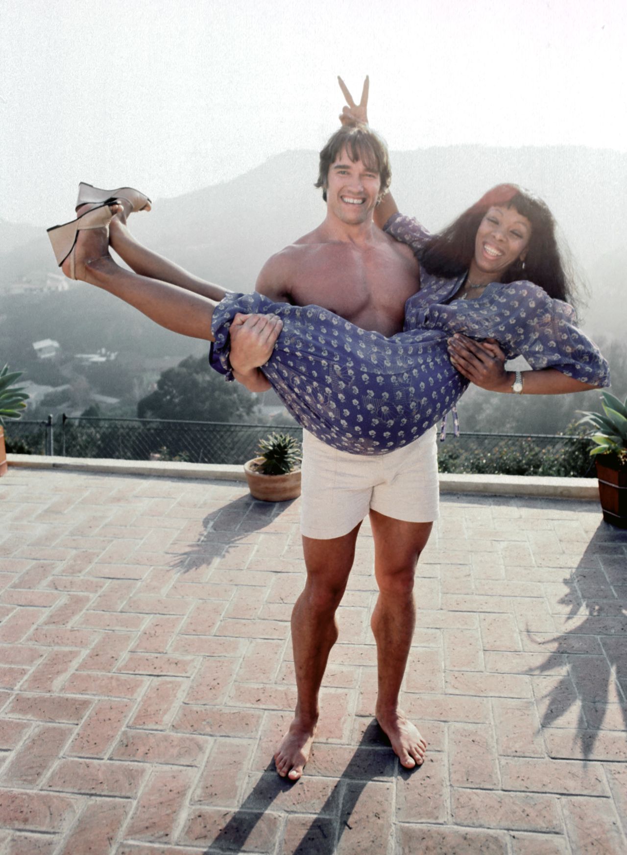 Summer gets a lift from future movie star and politician Arnold Schwarzenegger at her home in Los Angeles in April 1977.